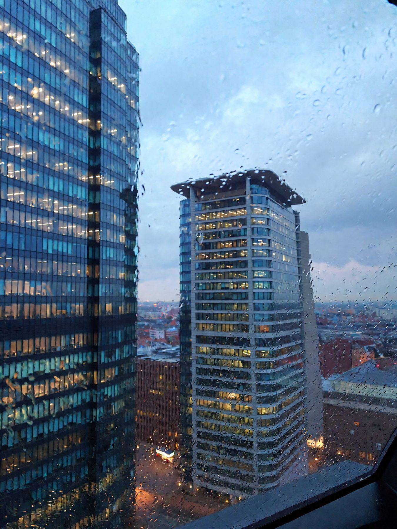 Financial district skyline through a rain-streaked glass facade
