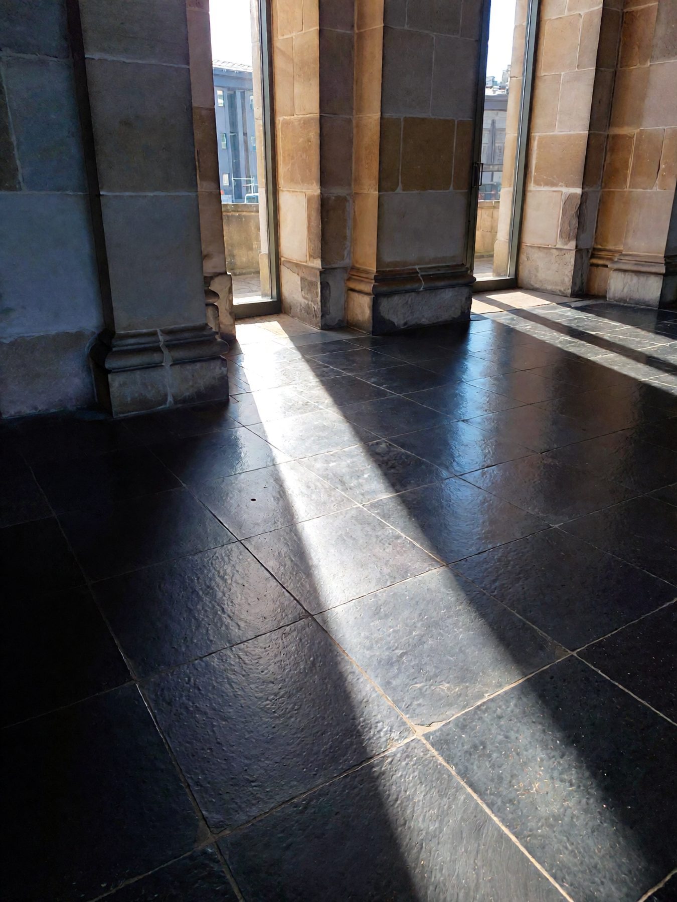 Shadows of stone pillars meeting on a polished floor